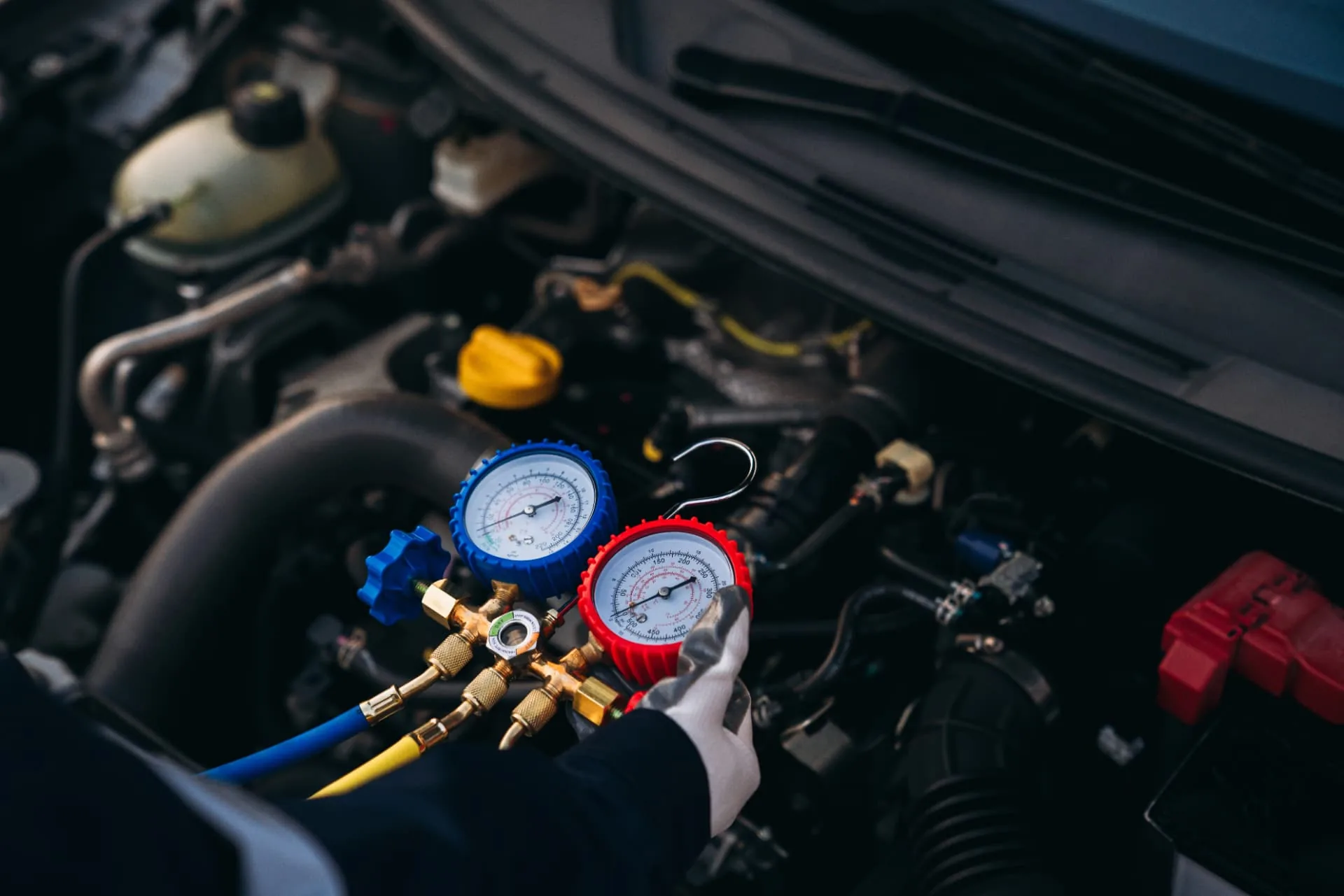 Mechanic checking AC pressure with gauges