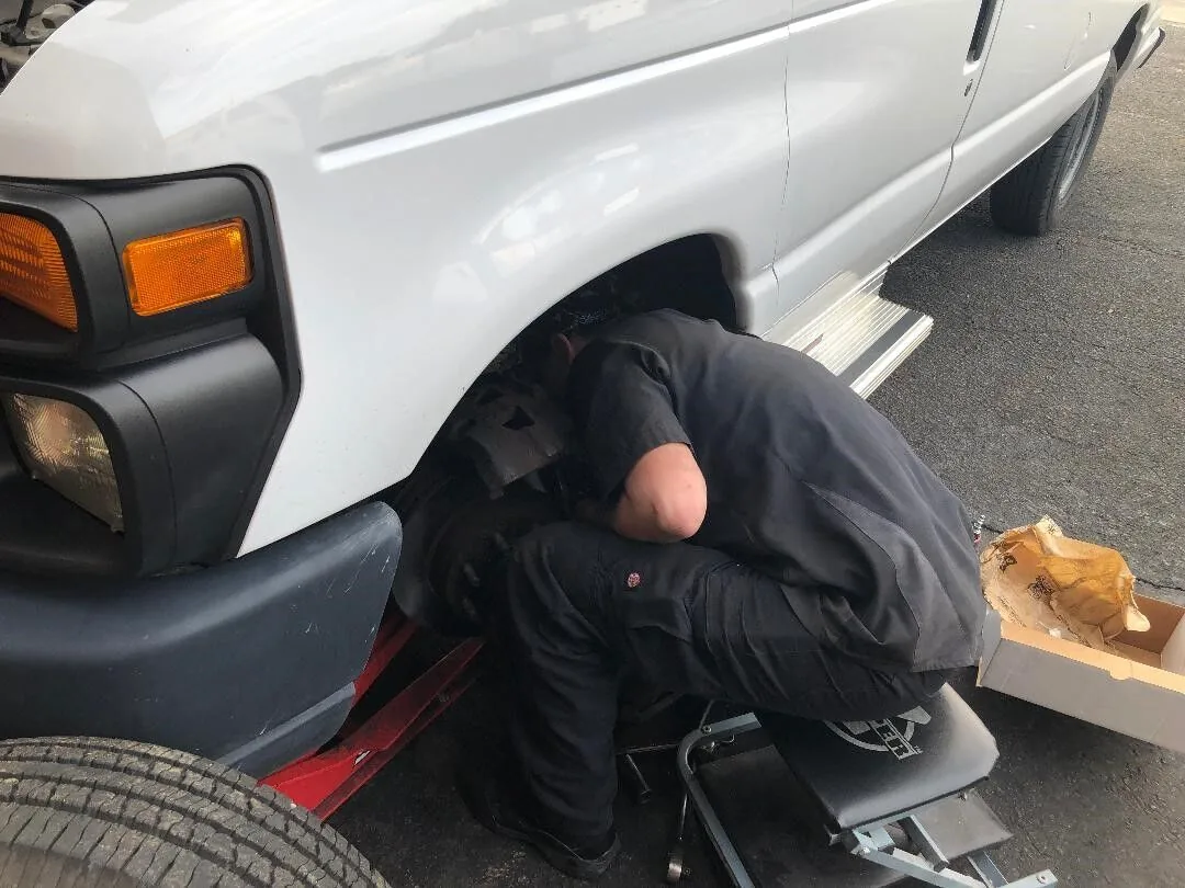 Technician working under a white van at Scott's Auto Repair in West Columbia, SC